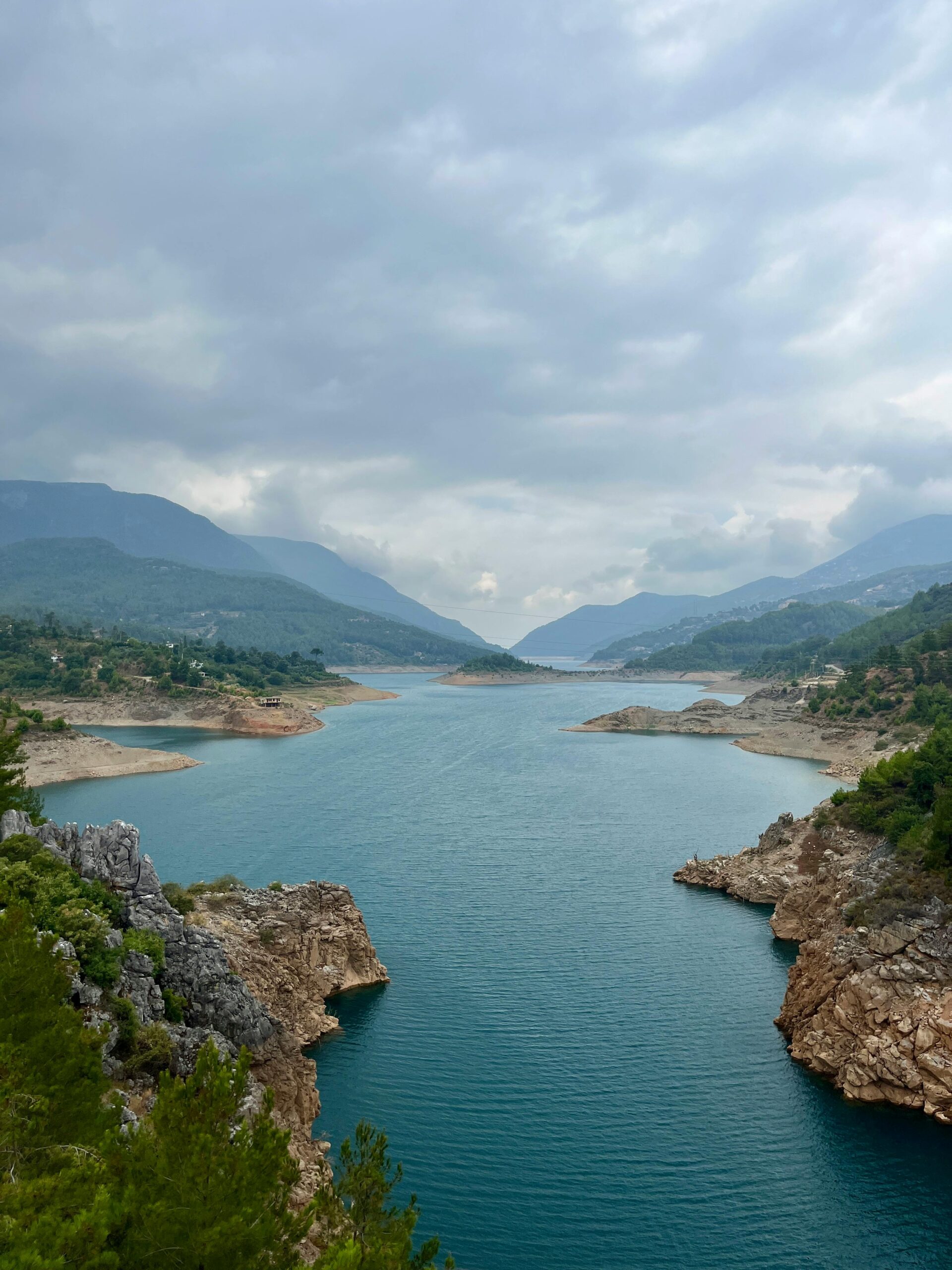 Vista panorâmica de um rio entre montanhas sob céu nublado — simboliza o fluxo emocional e os caminhos da vida nos sonhos com água.