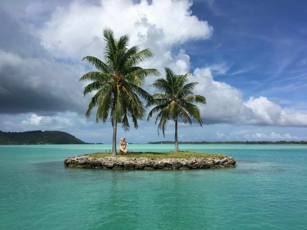 Pequena ilha com duas palmeiras e mar calmo, simbolizando simplicidade, paz e isolamento nos sonhos.