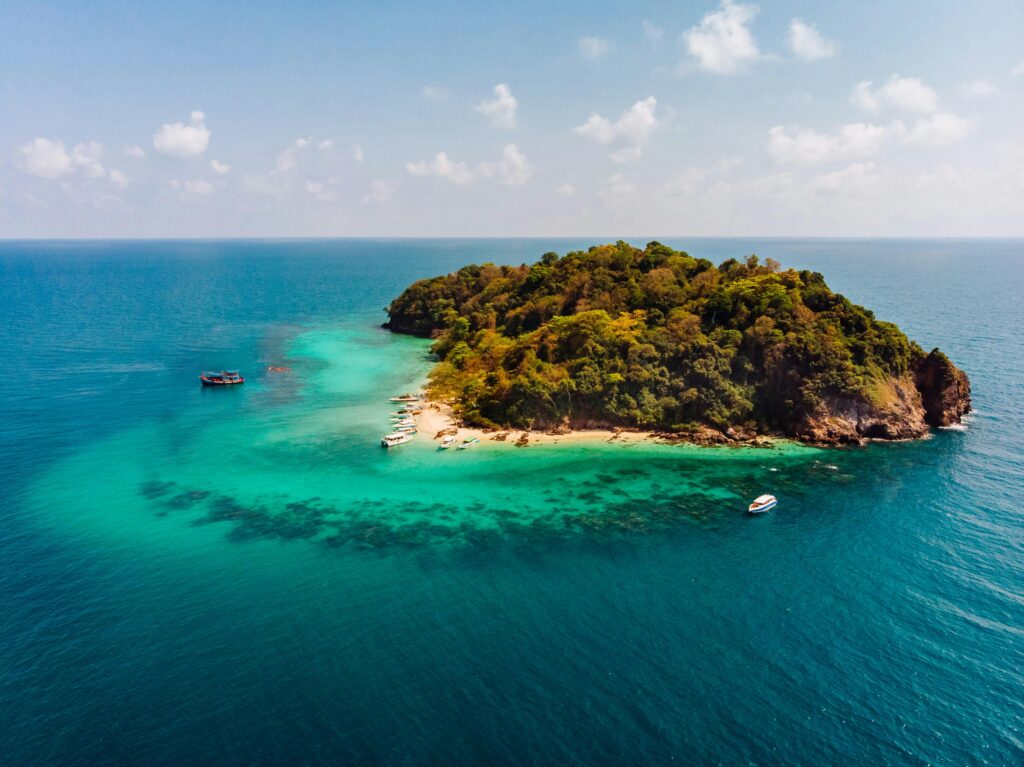 Ilha tropical com barcos atracados em mar cristalino, representando oportunidades e conexões ao sonhar com ilha.