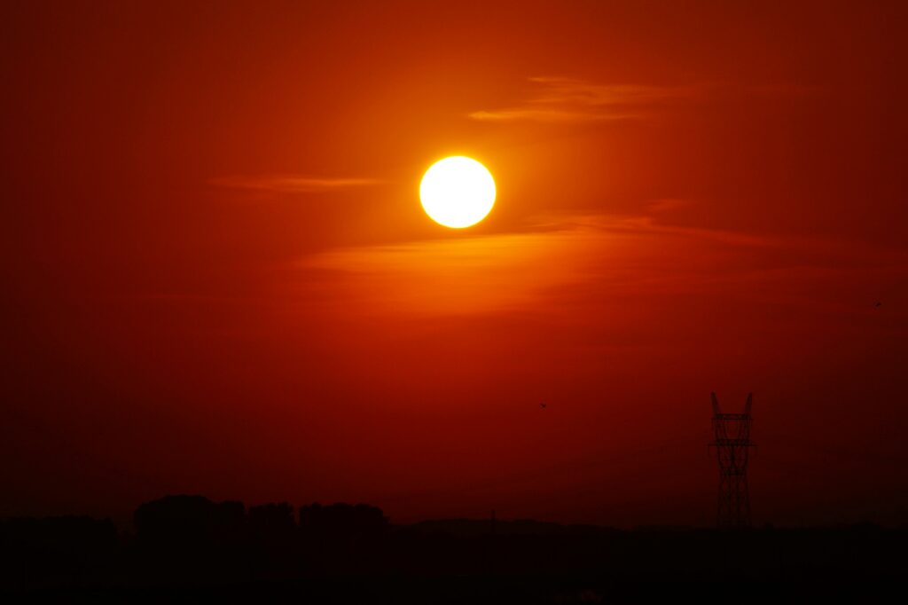 Sol intenso no horizonte avermelhado durante o pôr do sol simbolizando intensidade emocional e transformação nos sonhos.