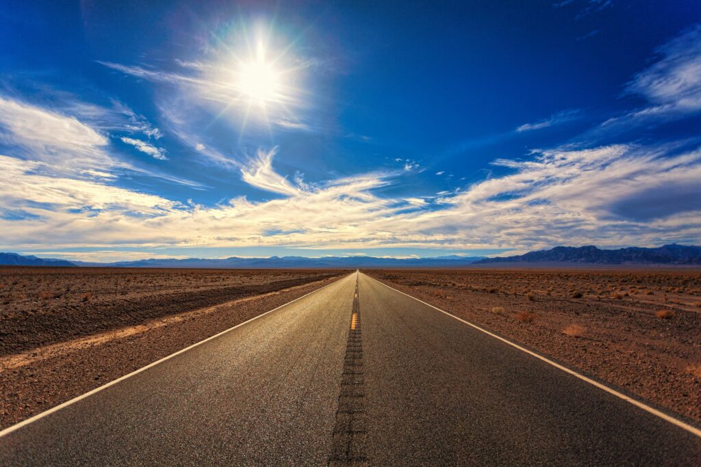 Estrada infinita no deserto com o sol forte no céu azul simbolizando clareza e novos caminhos nos sonhos.
