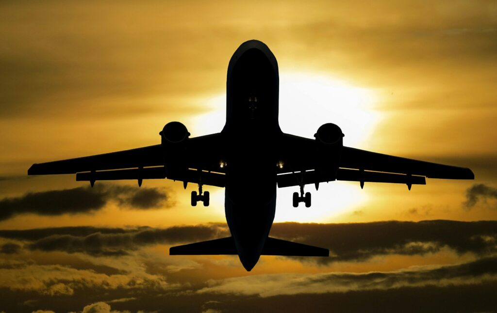 Silhueta de avião decolando em frente ao sol, sonho que simboliza novos objetivos e conquistas.