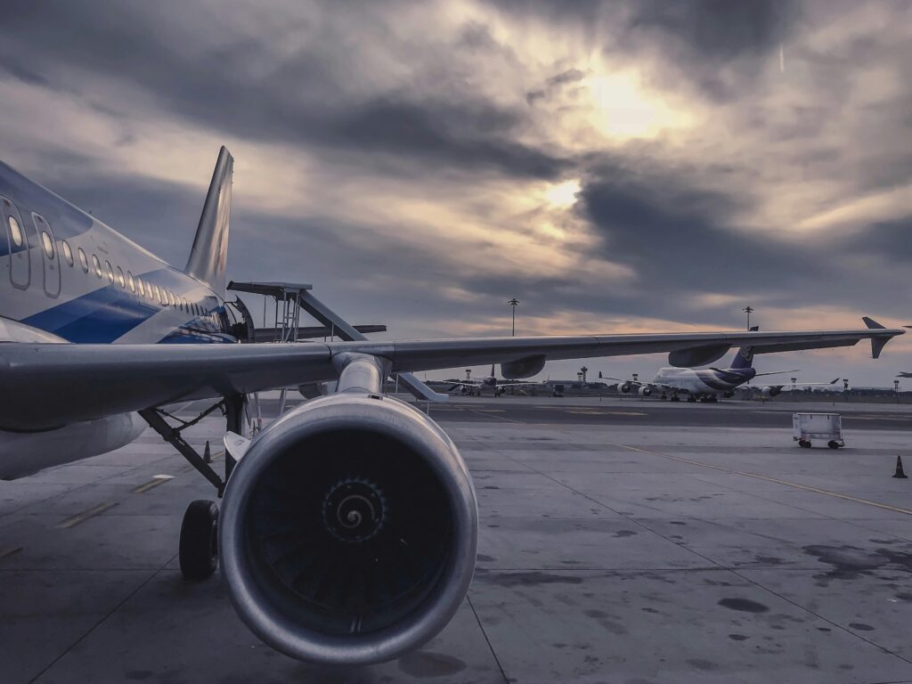 Avião comercial estacionado no aeroporto ao entardecer, sonho ligado a pausas e reflexões antes de mudanças.