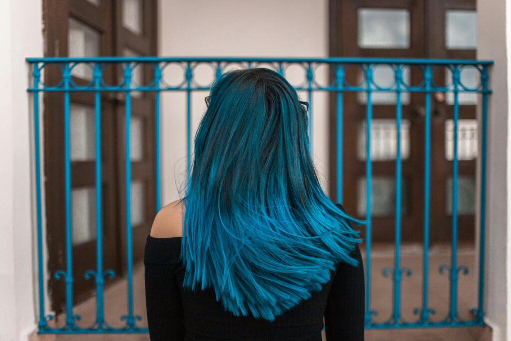 Mulher de costas com cabelo longo azul vibrante simbolizando transformação e mudanças ao sonhar com cabelo colorido.