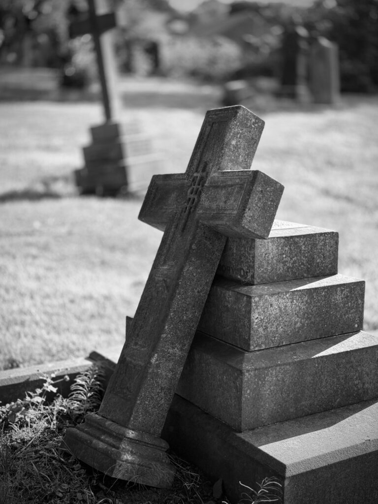 Cruz de pedra caída em cemitério antigo, relacionada a interpretações de sonhar com cemitério.