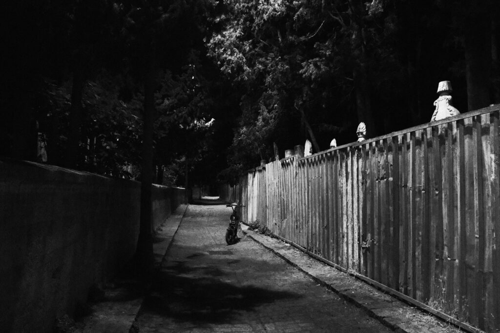 Caminho escuro e deserto ao lado de cemitério, simbolizando medo e insegurança em sonhos.