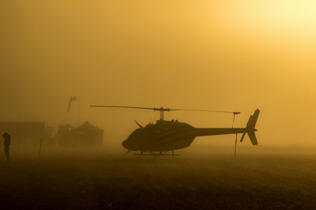 Helicóptero pousado em campo durante o nascer do sol, simbolizando novos começos nos sonhos.