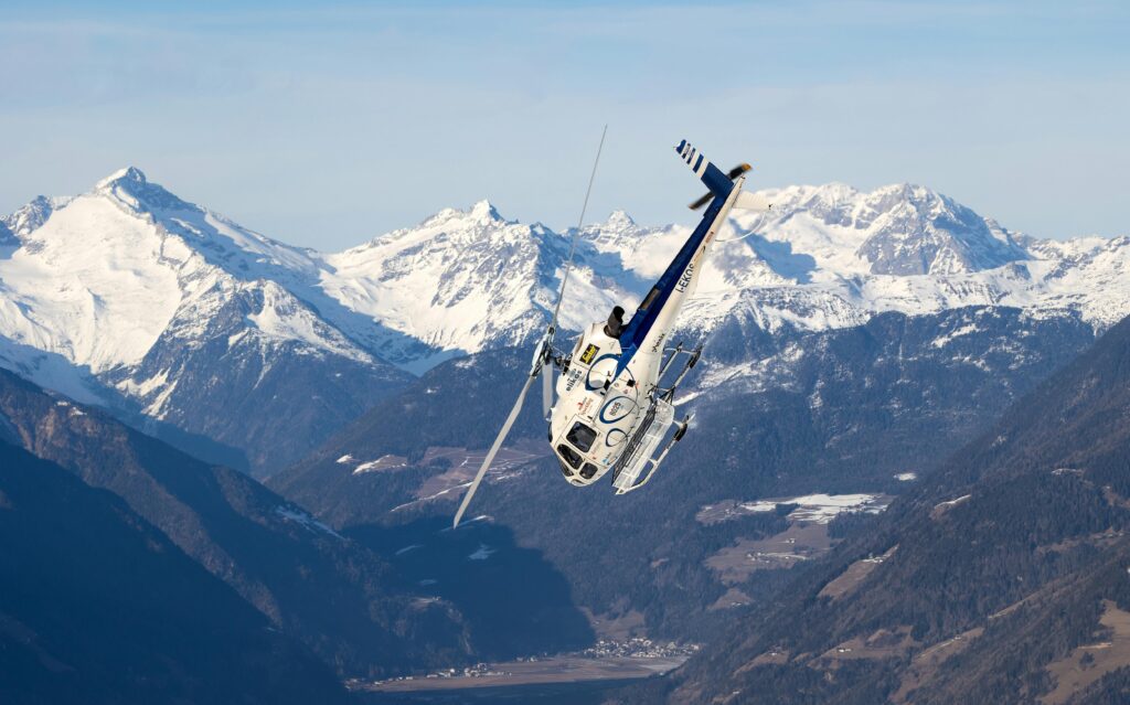 Helicóptero sobrevoando montanhas nevadas, representando sonhos com superação e liberdade.