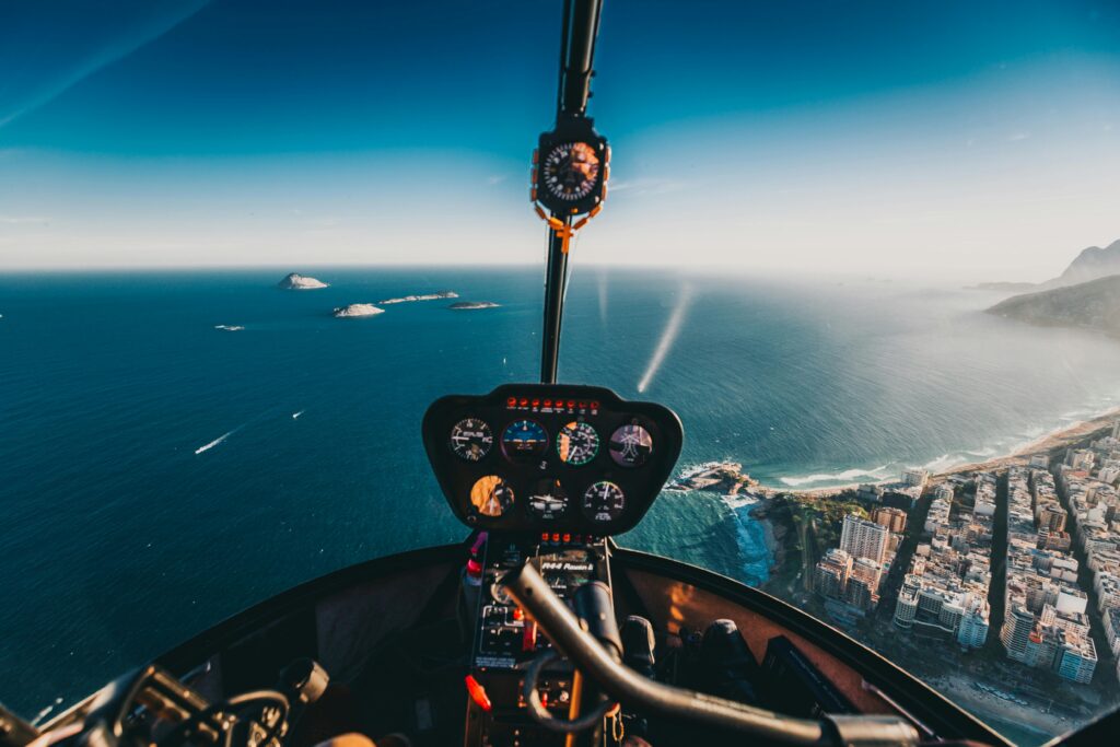 Vista de dentro de um helicóptero sobrevoando o mar e a cidade, ligado a sonhos de liberdade e novas perspectivas.