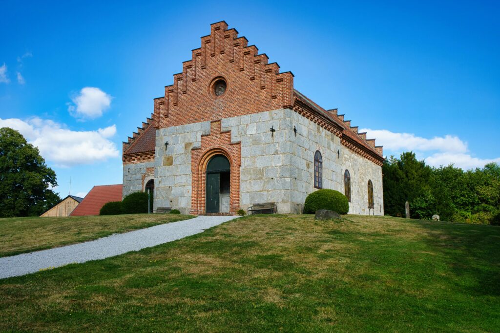 Fachada de uma igreja histórica de pedra e tijolos sob céu azul, representando sonhar com igreja.