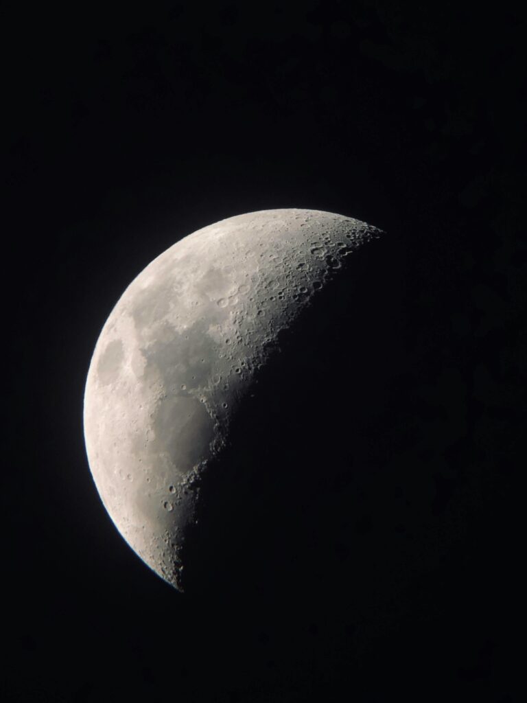 Lua em fase crescente com crateras bem definidas no céu escuro, simbolizando evolução espiritual e autoconhecimento nos sonhos.