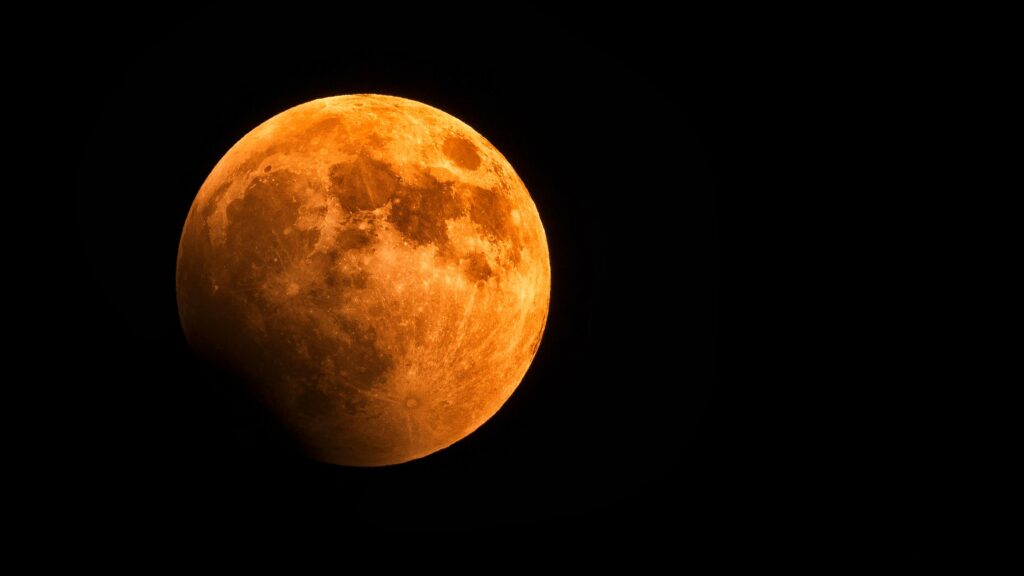 Lua cheia alaranjada brilhando intensamente no céu noturno, simbolizando paixão, intensidade e energia nos sonhos.