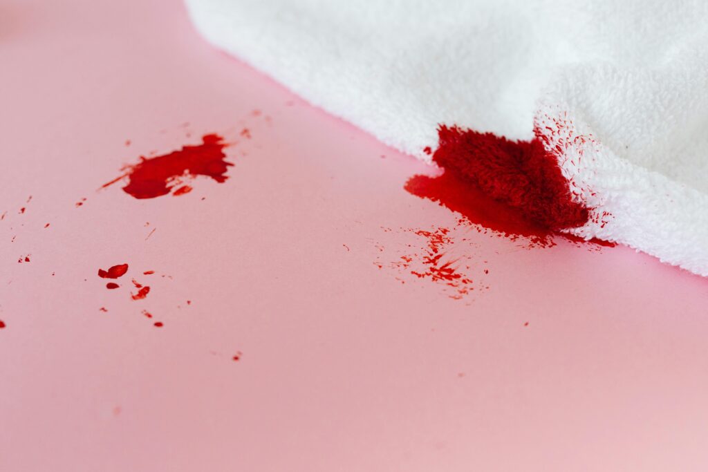 toalha manchada de sangue sobre superfície rosa, representando perda emocional e limpeza espiritual nos sonhos.