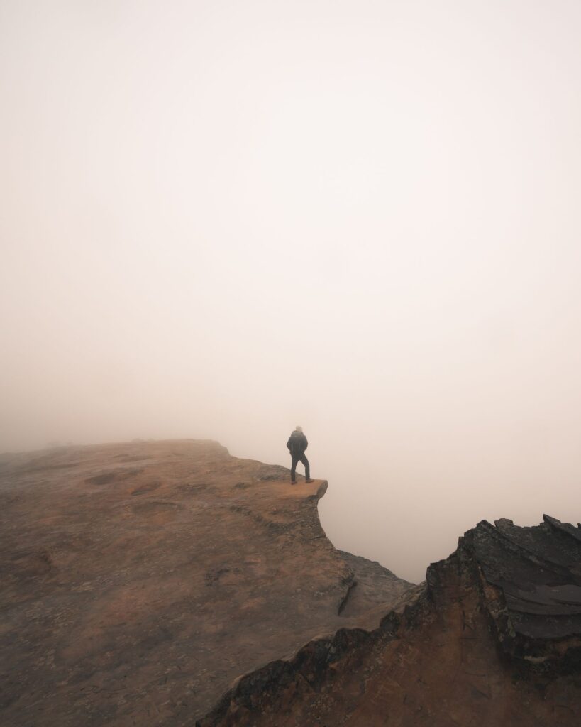 Pessoa à beira de um penhasco na neblina, sonho com abismo